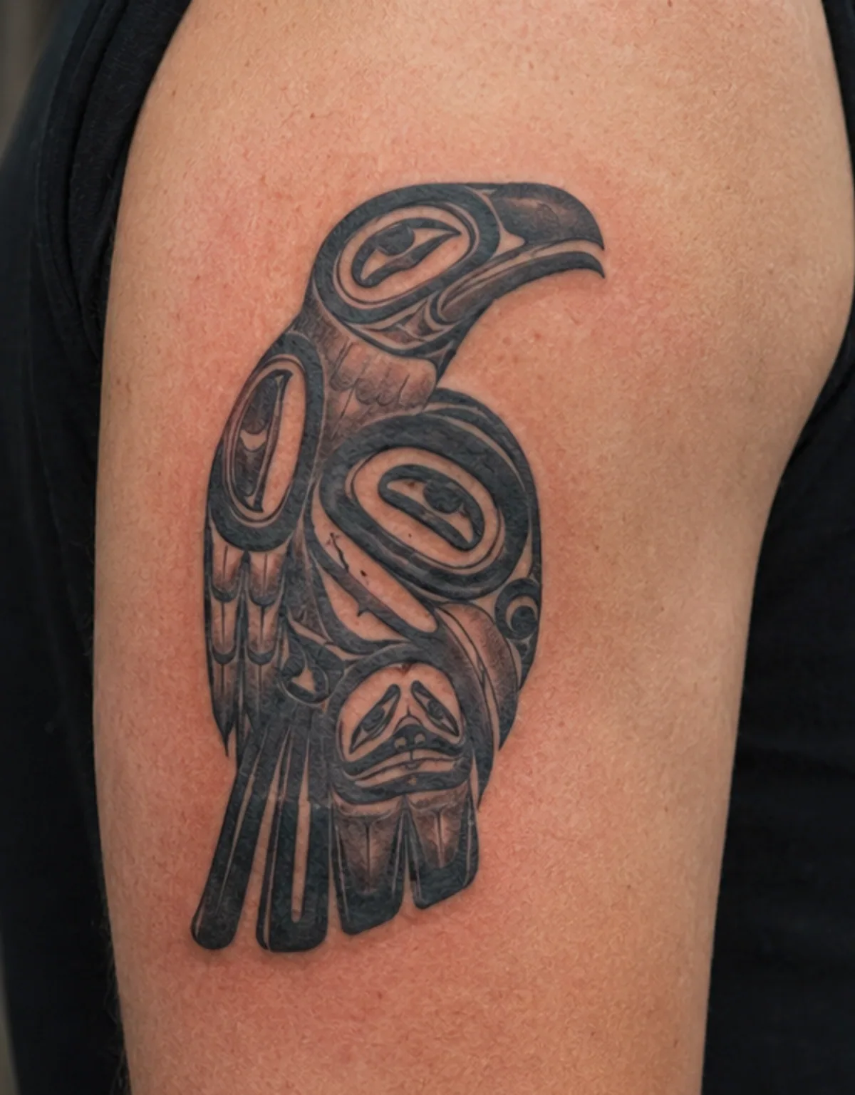 Black & grey tribal-tatuering av fågel på överarm — innan laserbehandling